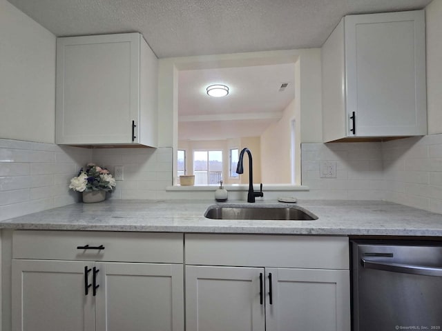 kitchen featuring stainless steel dishwasher, white cabinets, and a sink