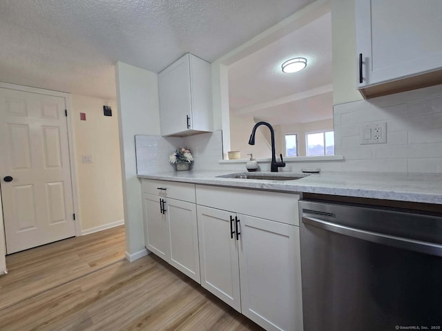 kitchen featuring a textured ceiling, a sink, light stone countertops, dishwasher, and light wood finished floors