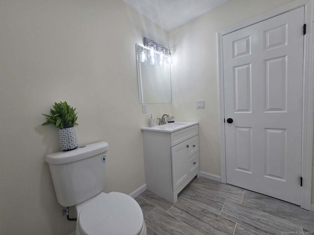 half bathroom with vanity, toilet, and baseboards