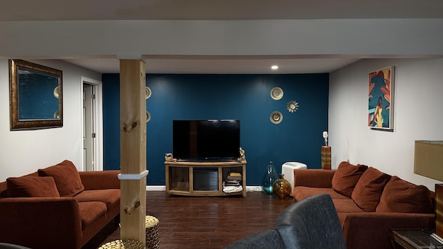 living room featuring decorative columns, baseboards, and wood finished floors