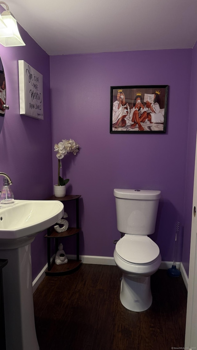 half bath featuring toilet, wood finished floors, and baseboards