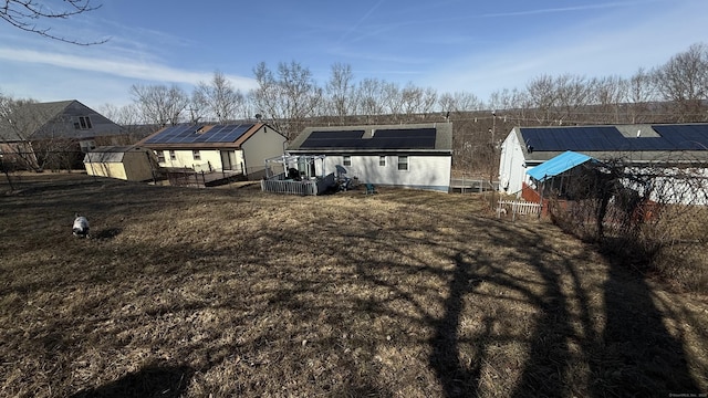 rear view of property with solar panels, an outdoor structure, a storage unit, and a yard