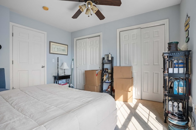 bedroom with carpet floors, a ceiling fan, and two closets