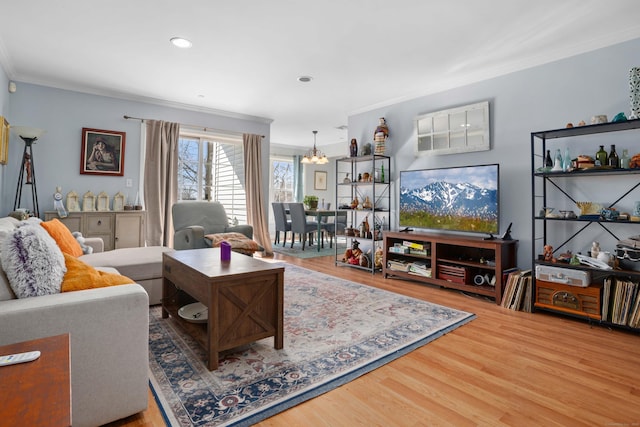 living area with ornamental molding, recessed lighting, an inviting chandelier, and wood finished floors