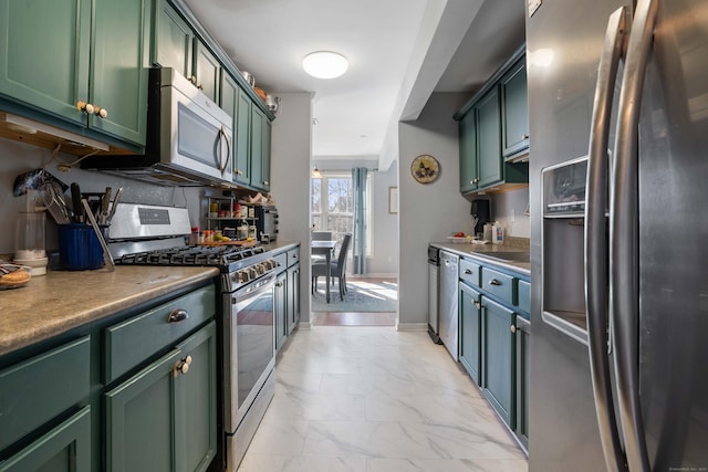 kitchen featuring tasteful backsplash, baseboards, appliances with stainless steel finishes, marble finish floor, and green cabinetry