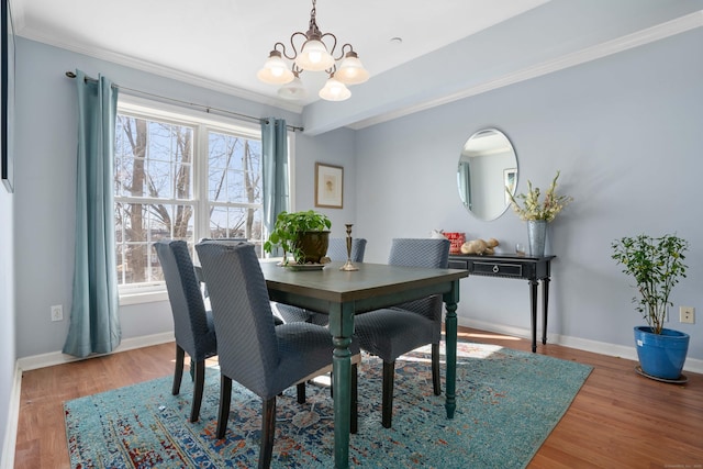 dining room with an inviting chandelier, baseboards, wood finished floors, and ornamental molding