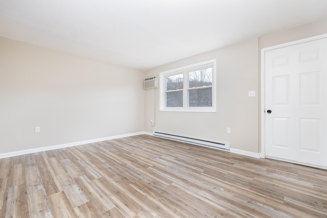 spare room with a baseboard heating unit, light wood finished floors, baseboards, and a wall unit AC