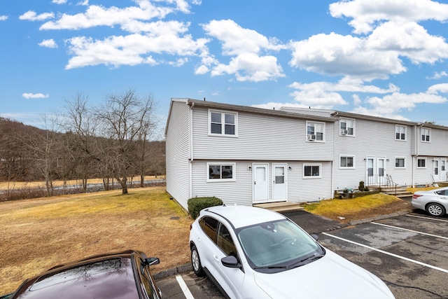 multi unit property featuring a front yard and uncovered parking