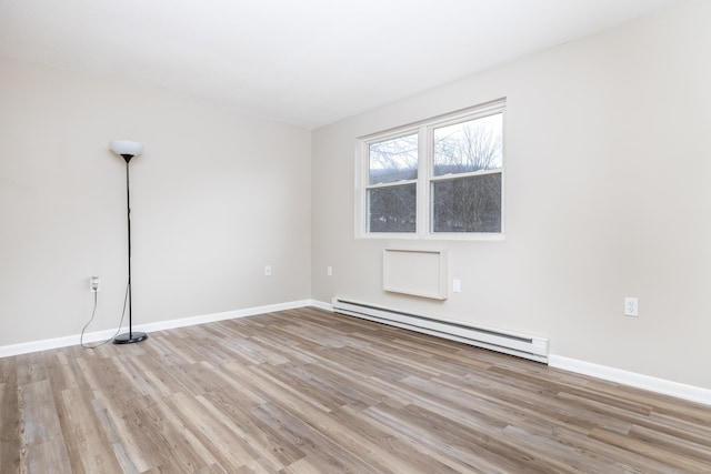 spare room with baseboards, baseboard heating, and light wood-style flooring