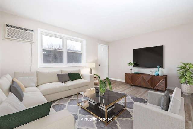 living area featuring an AC wall unit, baseboards, and wood finished floors