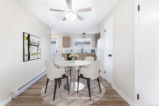 dining space featuring ceiling fan, light wood-type flooring, a baseboard heating unit, and baseboards