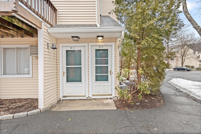 entrance to property featuring a shingled roof