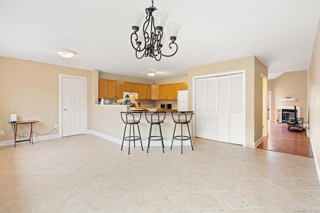 kitchen featuring pendant lighting, a breakfast bar area, freestanding refrigerator, and baseboards