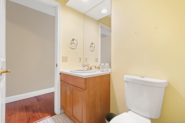 half bathroom with vanity, toilet, and baseboards