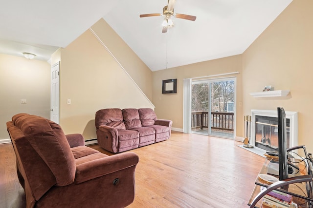 living room with light wood finished floors, lofted ceiling, a fireplace with flush hearth, a baseboard heating unit, and a ceiling fan