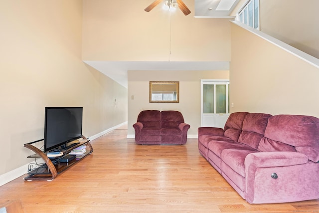 living room with light wood-style floors, ceiling fan, and baseboards