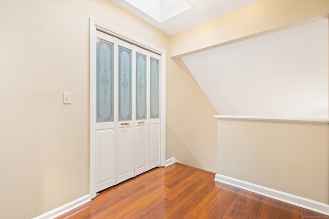 interior space with a skylight, baseboards, and wood finished floors