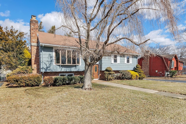 split foyer home featuring a chimney and a front lawn