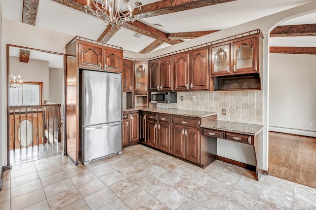 kitchen featuring stainless steel appliances, light stone counters, decorative backsplash, and an inviting chandelier