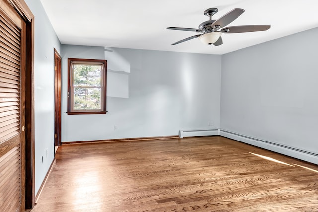 unfurnished room with a baseboard radiator, ceiling fan, baseboards, and wood finished floors