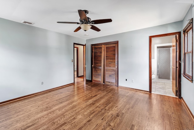 unfurnished bedroom with baseboards, light wood-style flooring, visible vents, and a closet