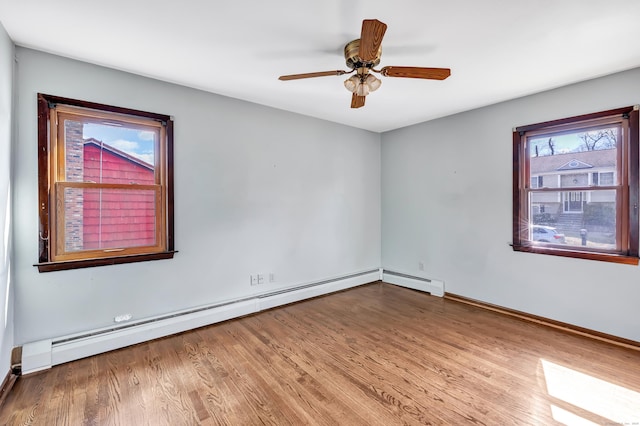 unfurnished room featuring a baseboard heating unit, ceiling fan, wood finished floors, and baseboards