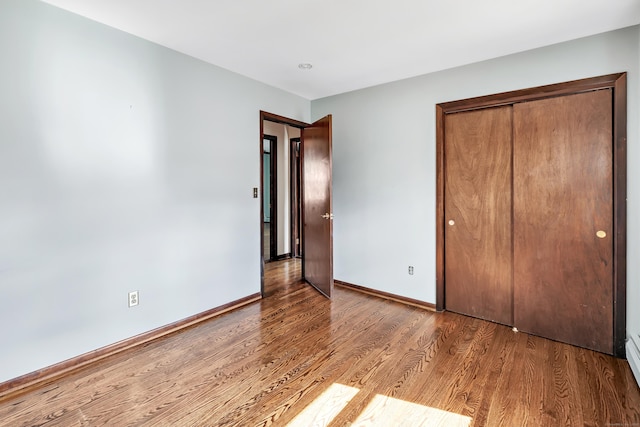 unfurnished bedroom with a closet, baseboards, and wood finished floors