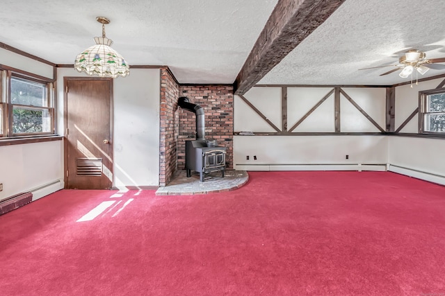 unfurnished living room featuring ceiling fan, ornamental molding, a wood stove, carpet, and a textured ceiling