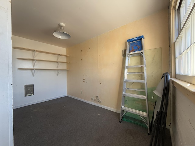 spare room featuring baseboards and dark carpet