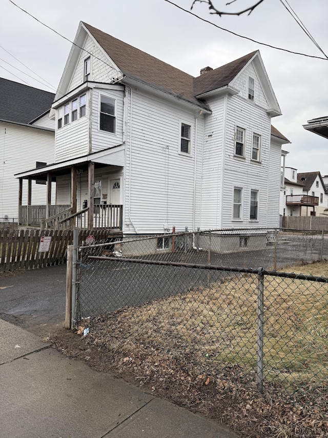 view of side of home featuring a fenced front yard and covered porch