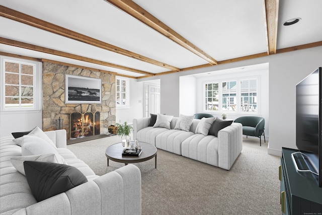 carpeted living area featuring beamed ceiling, a fireplace, and a wealth of natural light