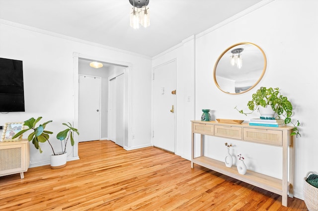 entryway with ornamental molding, baseboards, and light wood finished floors