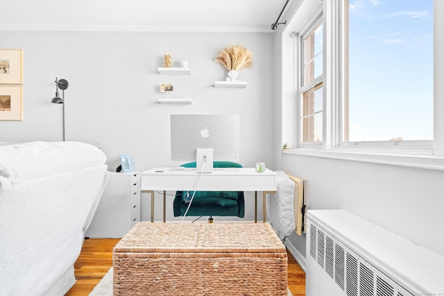 office space featuring light wood-style floors, radiator heating unit, and crown molding