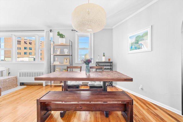 dining area featuring radiator, baseboards, crown molding, and wood finished floors