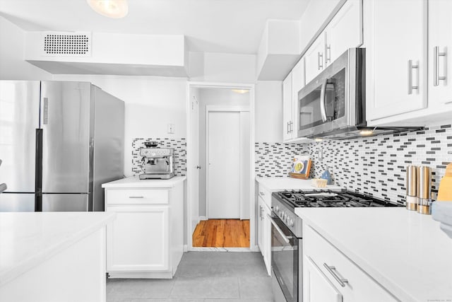 kitchen with visible vents, white cabinets, light countertops, appliances with stainless steel finishes, and tasteful backsplash