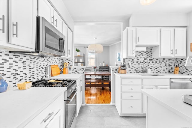 kitchen with white cabinets, appliances with stainless steel finishes, light countertops, and a sink