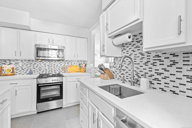 kitchen featuring white cabinets, stainless steel appliances, a sink, and light countertops