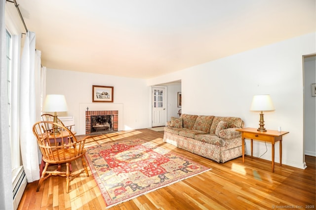 living area featuring a fireplace, a baseboard heating unit, and hardwood / wood-style floors