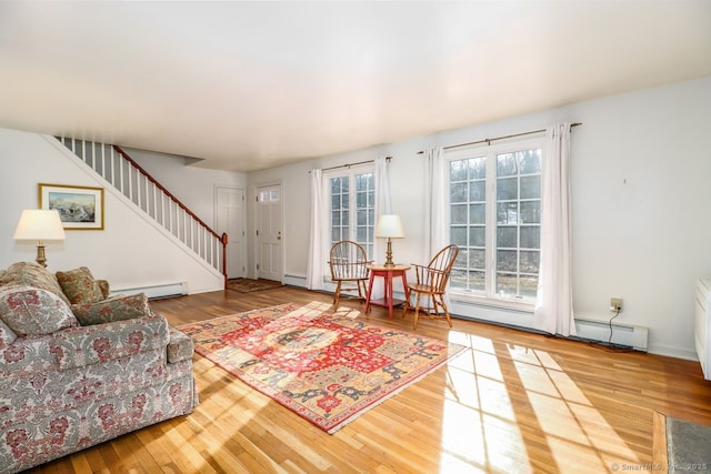 living area featuring baseboards, stairway, baseboard heating, and wood finished floors