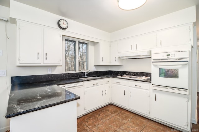 kitchen featuring white appliances, under cabinet range hood, white cabinetry, and a sink