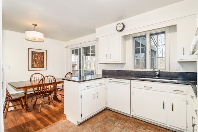 kitchen featuring white cabinetry, white dishwasher, a peninsula, and a sink