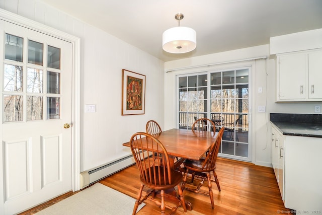 dining room with light wood-type flooring and a baseboard heating unit