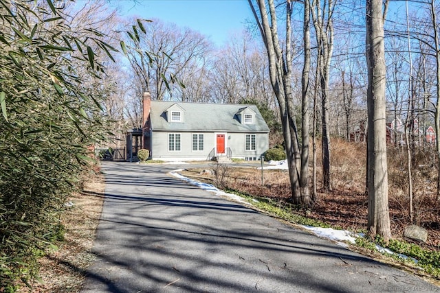 cape cod home featuring aphalt driveway and a chimney