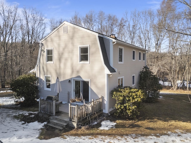 exterior space with a chimney, a wooden deck, and a gambrel roof