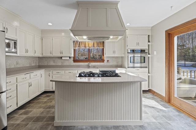 kitchen with white cabinets, a center island, stainless steel appliances, premium range hood, and backsplash