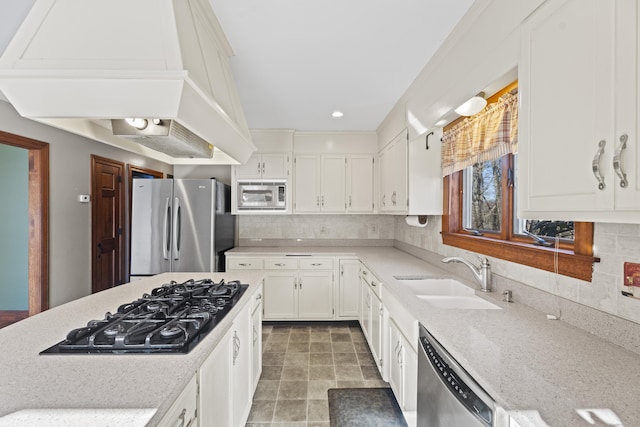 kitchen with a sink, white cabinetry, appliances with stainless steel finishes, backsplash, and custom range hood