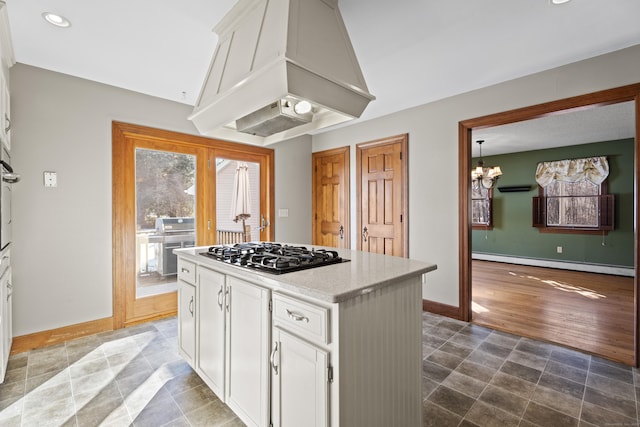 kitchen with baseboard heating, white cabinetry, black gas stovetop, premium range hood, and baseboards