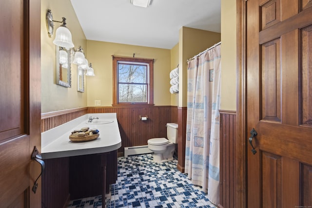 bathroom featuring toilet, a wainscoted wall, a baseboard heating unit, wood walls, and vanity