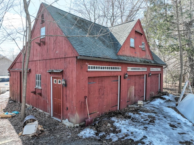 view of side of home featuring a garage, a shingled roof, a barn, and an outdoor structure