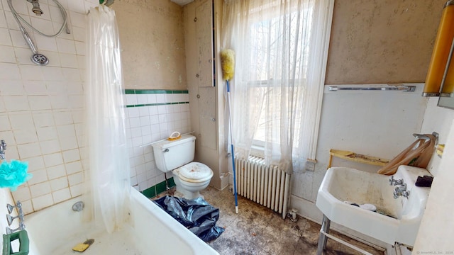 bathroom with toilet, plenty of natural light, radiator heating unit, and tile walls